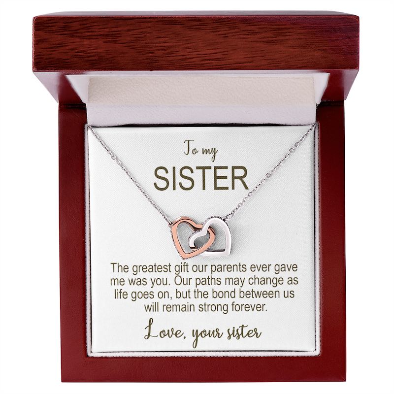 Necklace with interlocking heart pendants in a wooden box with a message for a sister.