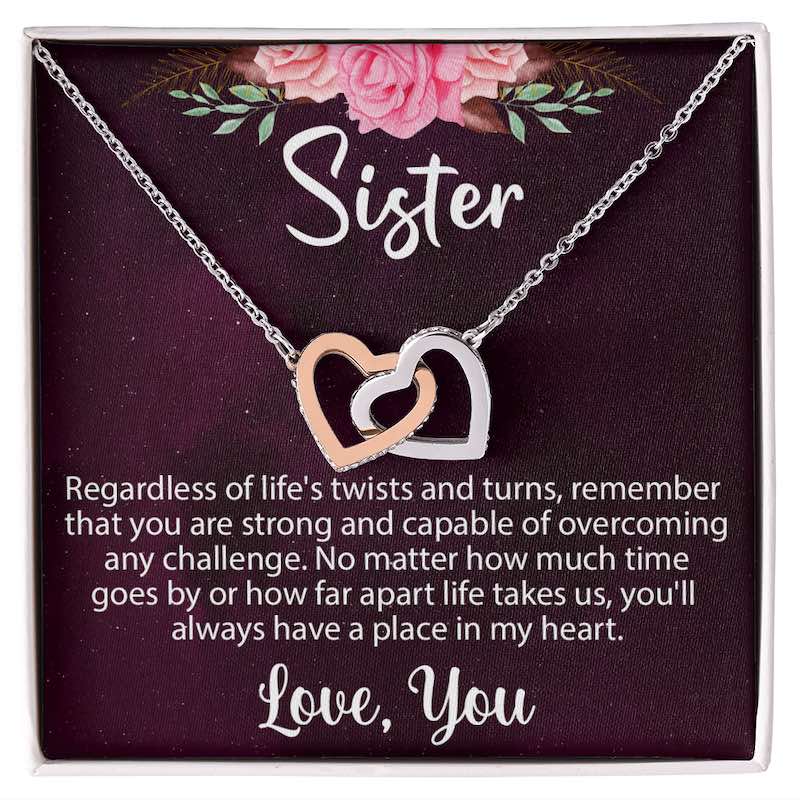 Sister gifts: Interlocking rose gold and silver heart necklace in a gift box with a message card featuring pink floral accents.