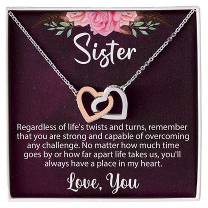 Sister gifts: Interlocking rose gold and silver heart necklace in a gift box with a message card featuring pink floral accents.