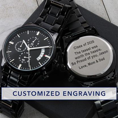 custom grad gifts: black wristwatch with engraved message on a black gift box against a gray surface.