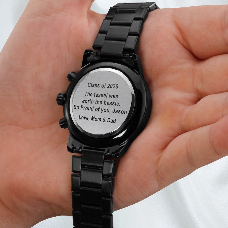 college grad gifts: black watch with engraved message held by a hand.