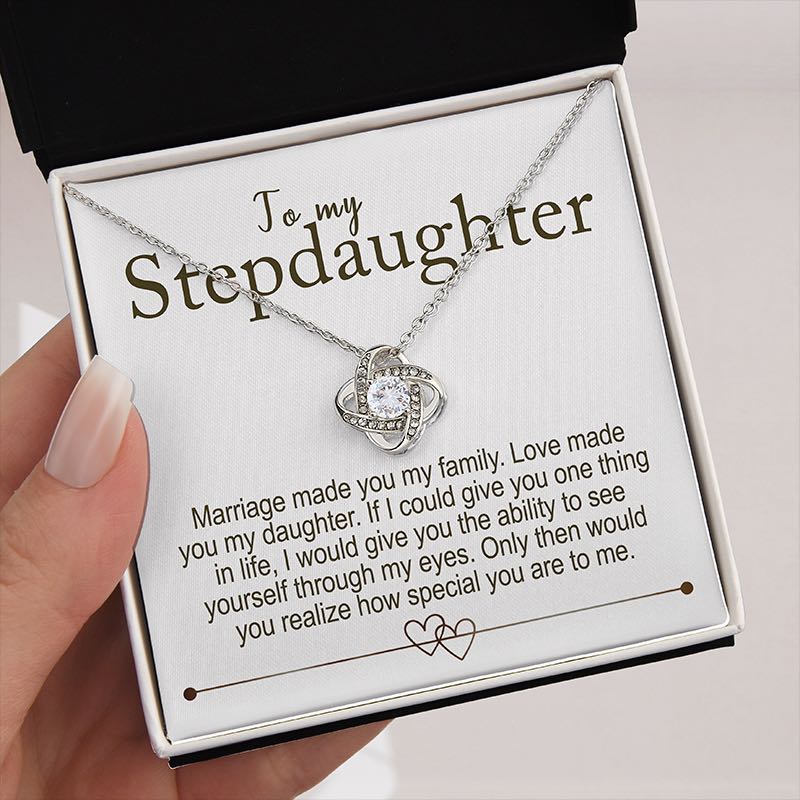 Necklace with a message card for stepdaughter in a box kept by a hand on a creamy background 