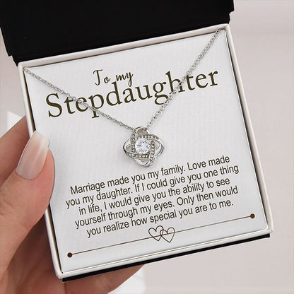 Necklace with a message card for stepdaughter in a box kept by a hand on a creamy background 