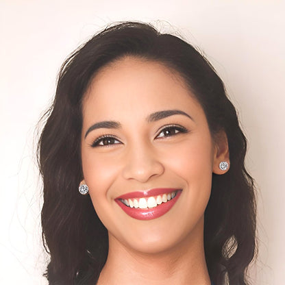Woman with dark hair and cubic zirconia stud earrings against a plain background