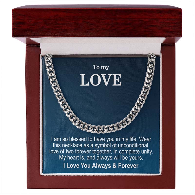 A silver cuban link chain necklace presented inside an open reddish-brown wooden gift box with a blue message card that reads 'To my LOVE' and a sentimental message, presented on a white background.