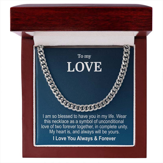 A silver cuban link chain necklace presented inside an open reddish-brown wooden gift box with a blue message card that reads 'To my LOVE' and a sentimental message, presented on a white background.