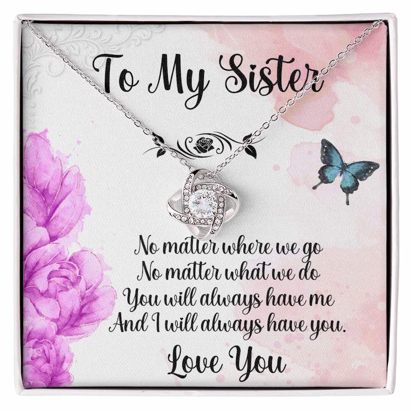 Personalized gifts for sister: A white gift box displaying a love knot necklace with a purple floral and butterfly sister message card.
