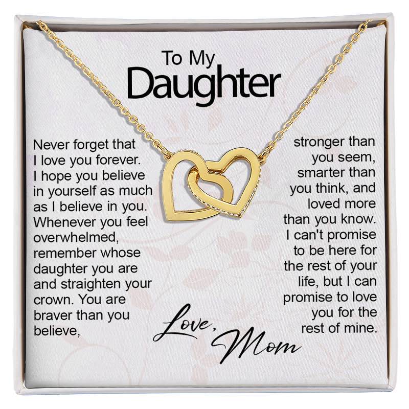 A gold double-heart pendant necklace presented on a white gift card inside a gift box, with sentimental text addressed to a daughter and the words 'Love, Mom' at the bottom.