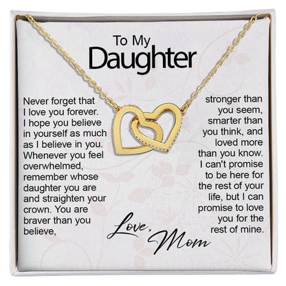 A gold double-heart pendant necklace presented on a white gift card inside a gift box, with sentimental text addressed to a daughter and the words 'Love, Mom' at the bottom.