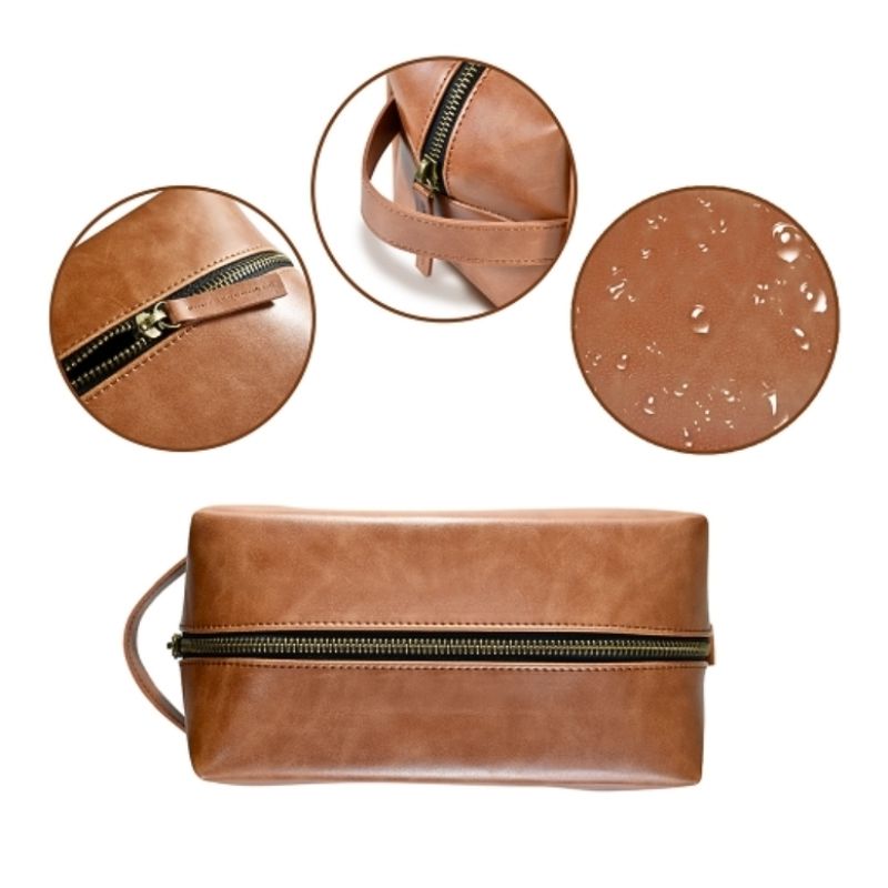 Detail view of a brown PU leather toiletry bag featuring a top zipper closure, sturdy side carrying handle, and water-resistant leather finish shown with water droplets.