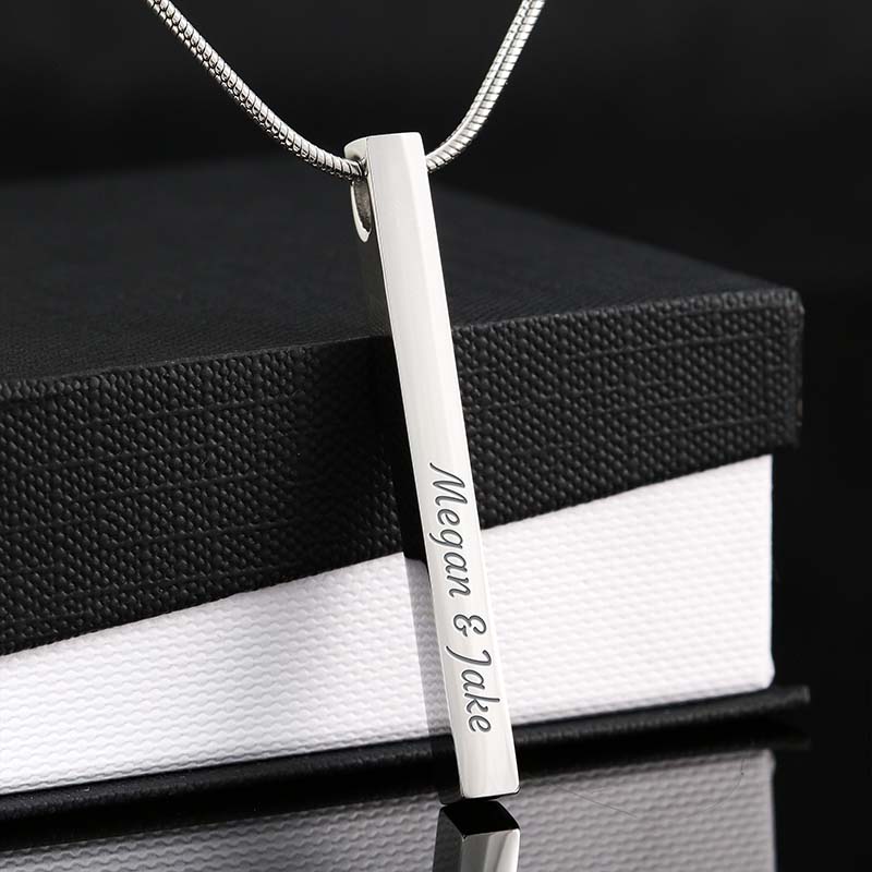 Silver bar pendant with engraved names on a black and white box background