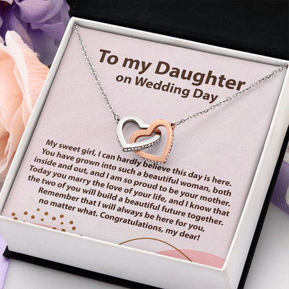 A silver double-heart necklace with one rose-gold heart and a clear crystal-studded border, presented in a gift box on a pink message card for a daughter's wedding day.