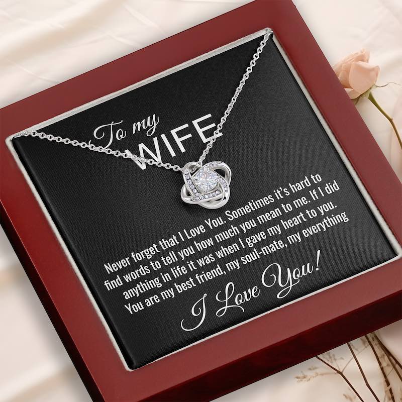 Silver necklace with heart pendant on a personalized card for a wife, placed on a wooden surface.