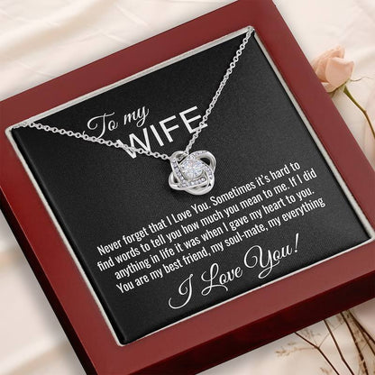 Silver necklace with heart pendant on a personalized card for a wife, placed on a wooden surface.