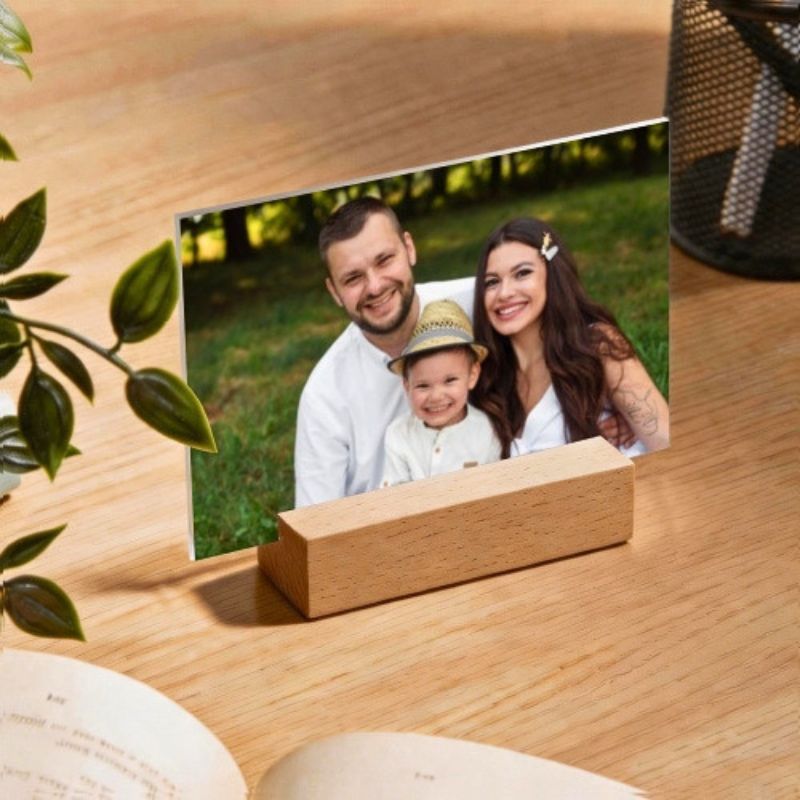Acrylic photo frame with wooden base displaying a printed family photo on a table