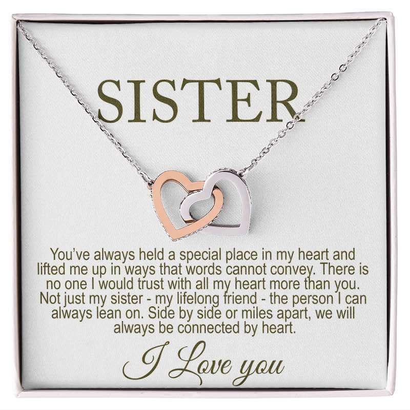 Necklace with interlocking heart pendants on a card that reads 'Sister' and a sentimental message.