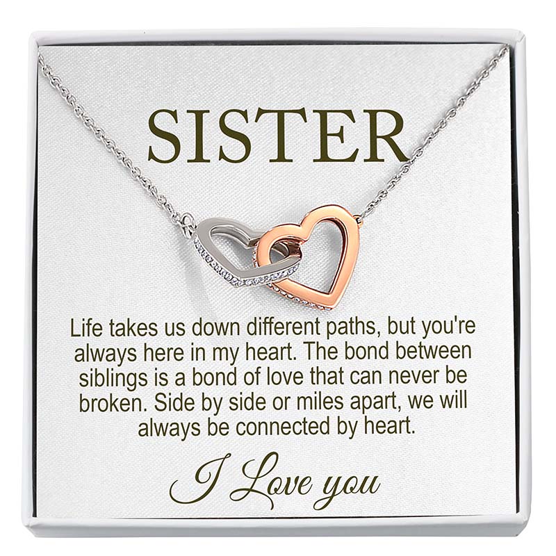 Necklace with interlocking heart pendants on a card that reads 'Sister' and sentimental message.