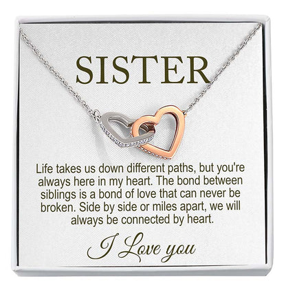 Necklace with interlocking heart pendants on a card that reads 'Sister' and sentimental message.